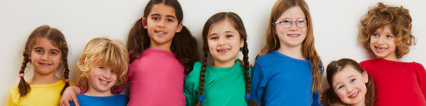 A group of seven young girls with diverse hair and skin tones, smiling and posing together against a plain white background.