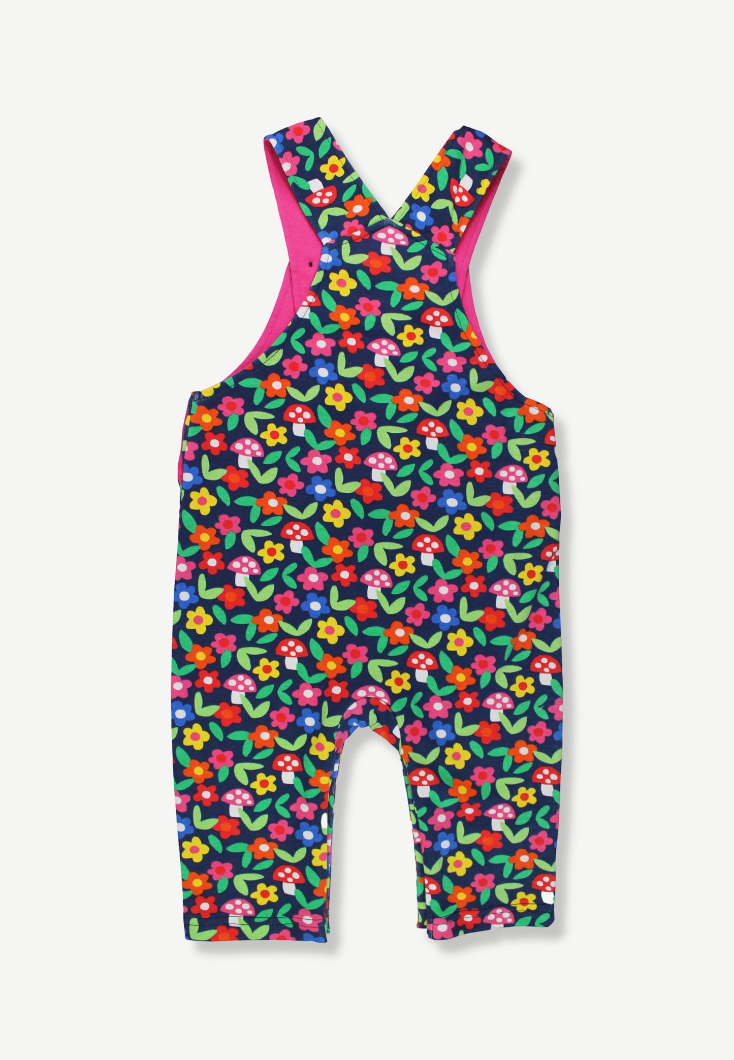 A baby romper with an all-over colorful floral print on a dark green background, featuring bright pink shoulder straps and a matching pink inner lining, shown against a light gray background.