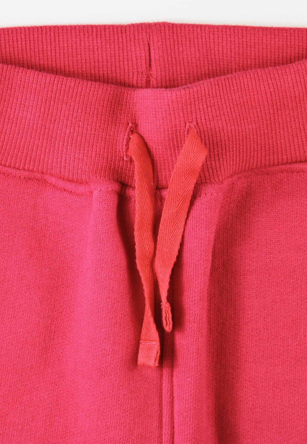 Close-up of red sweatpants with a drawstring on a white background