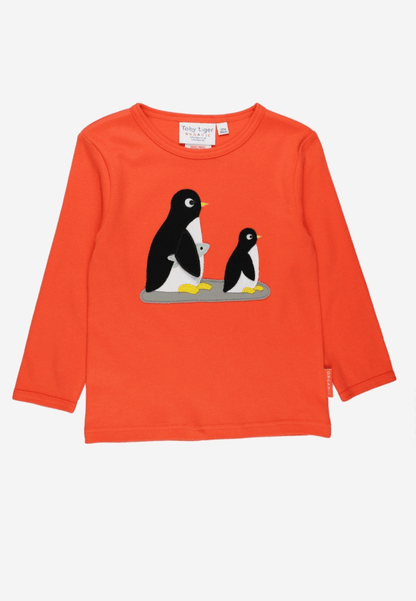 A bright orange long-sleeve children's top featuring a graphic of two penguins on the chest, displayed flat against a light off-white background.