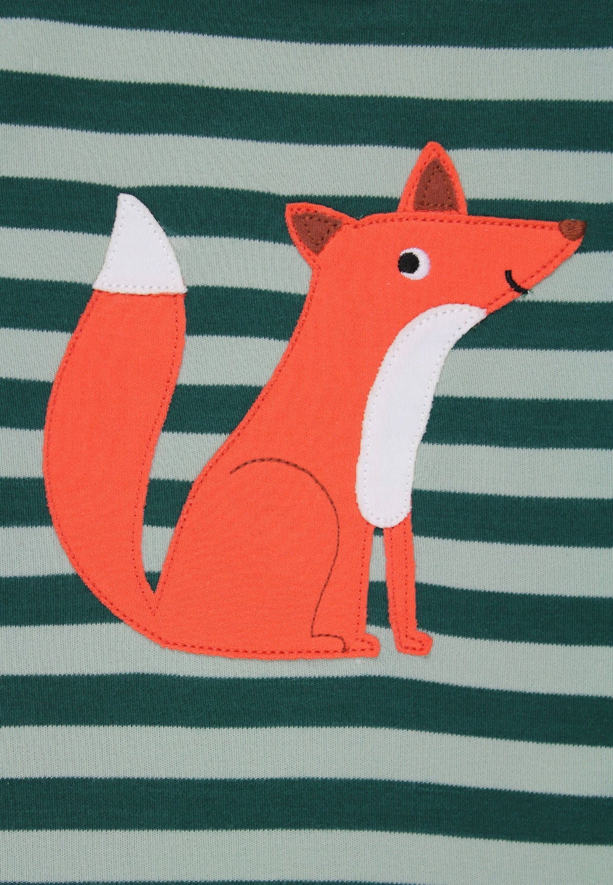 A close-up of a children's garment featuring a stylized orange fox applique with a white chest and white-tipped tail, set against a dark green and light gray striped fabric background.