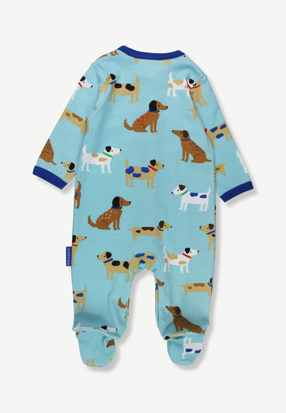 A baby footed one-piece jumpsuit in light blue, featuring an all-over print of cartoon dachshunds in various colors, with dark blue trim on the collar and cuffs.