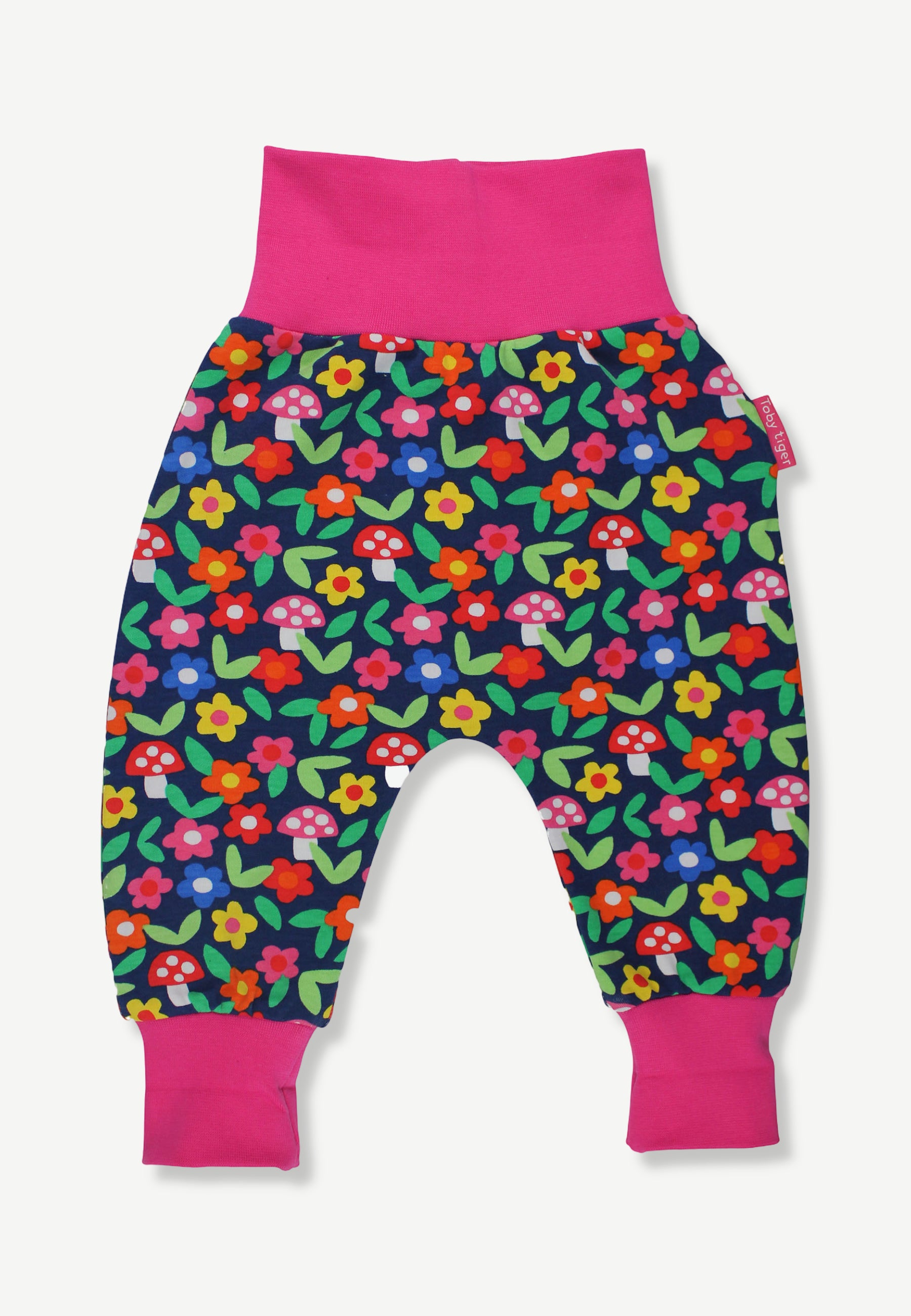 A pair of baby jogger pants featuring a colorful floral and mushroom print on a navy blue background, with bright pink elastic waistband and leg cuffs.