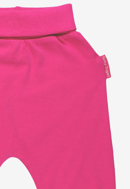 Bright pink knit pants with a wide elastic waistband and a small side tag reading 'baby tiger' in white text, shown on a light gray background.