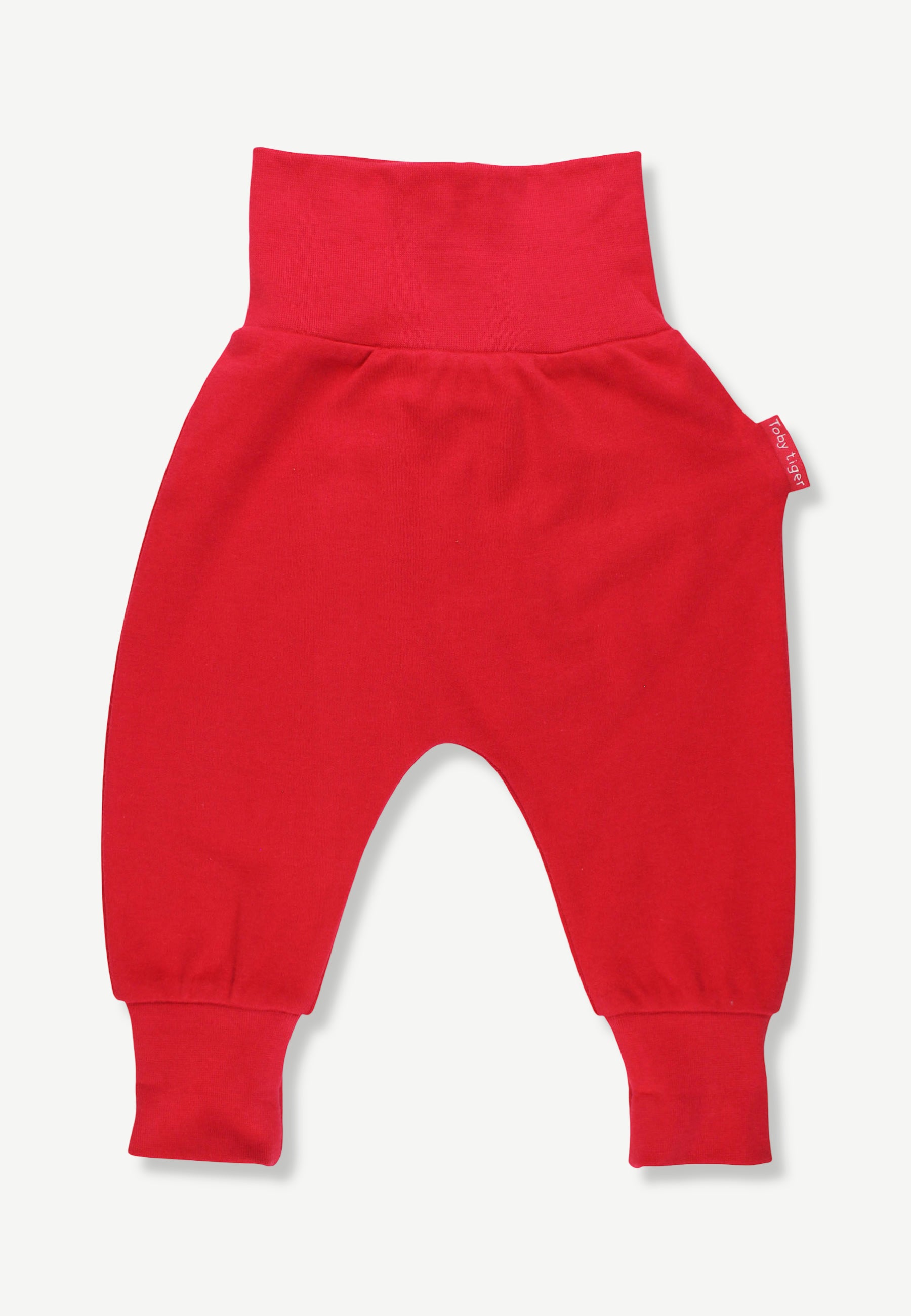 A pair of bright red baby pants with a wide elastic waistband and cuffed ankles, shown flat against a light off-white background.