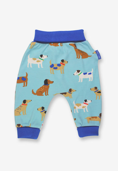 Light blue baby jogger pants with a playful all-over print of cartoon dogs, featuring solid royal blue elastic waistband and ribbed ankle cuffs, shown on a light gray background.