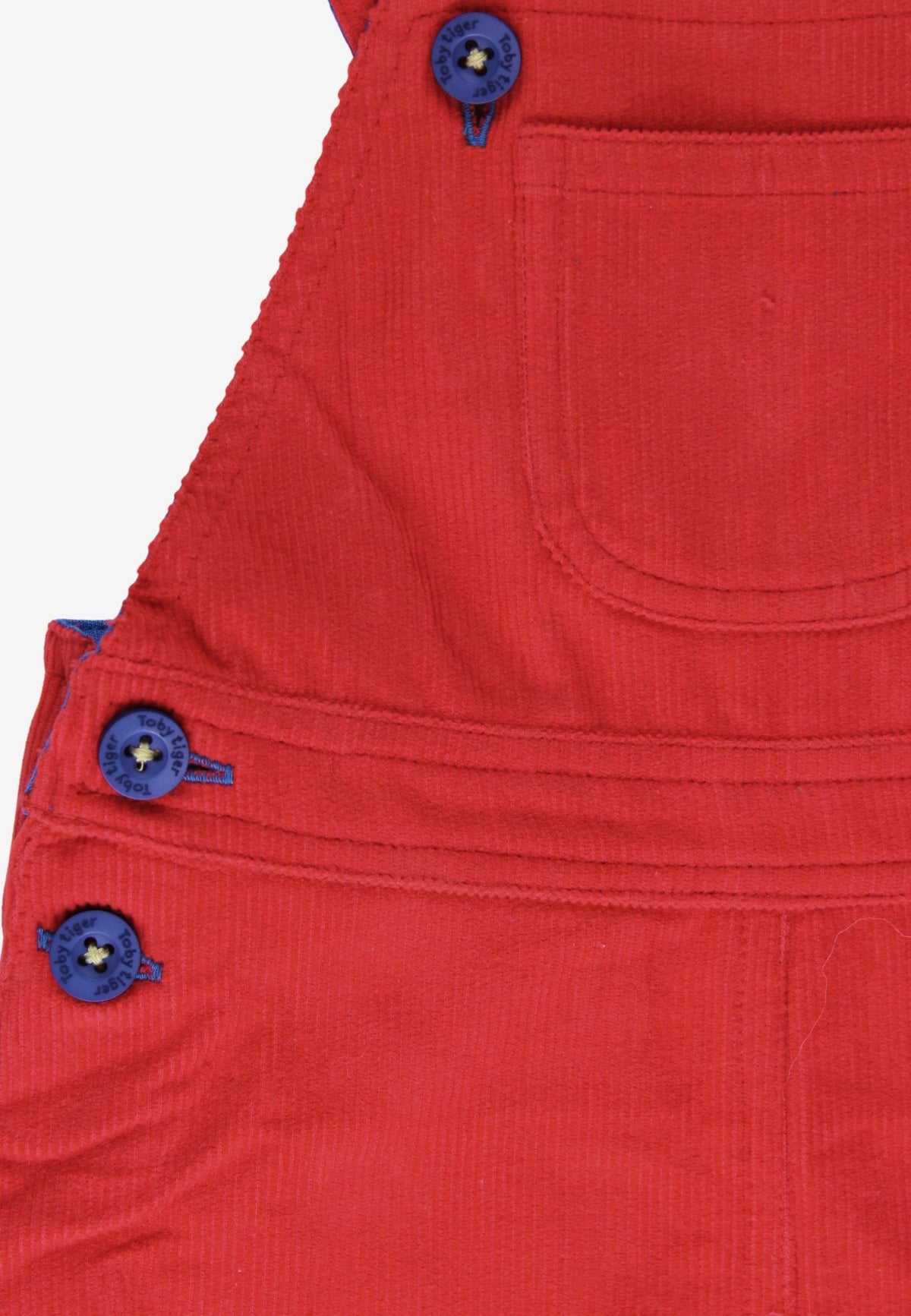 Close-up of a red corduroy bib overalls featuring blue buttons and a front pocket, set against a plain white background.
