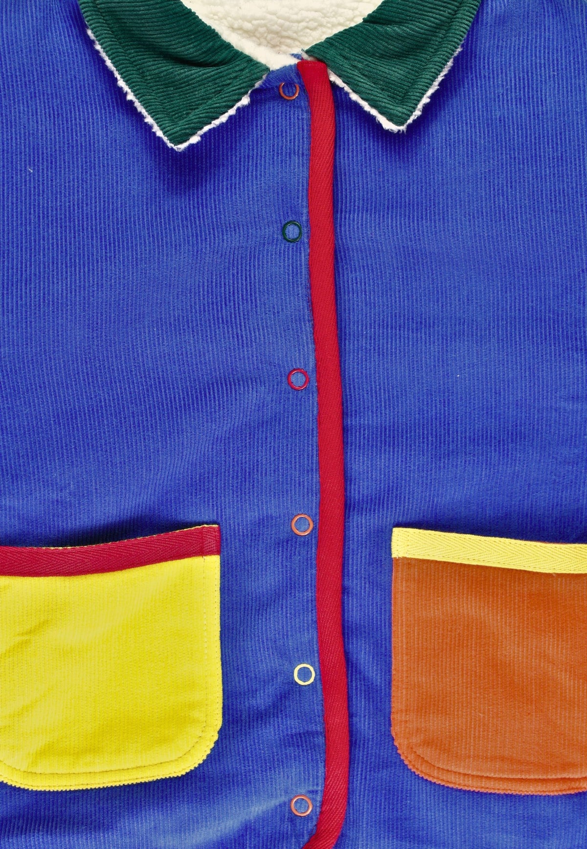 Colorful jacket with blue body, green collar, red lining, yellow pocket, and brown patch.