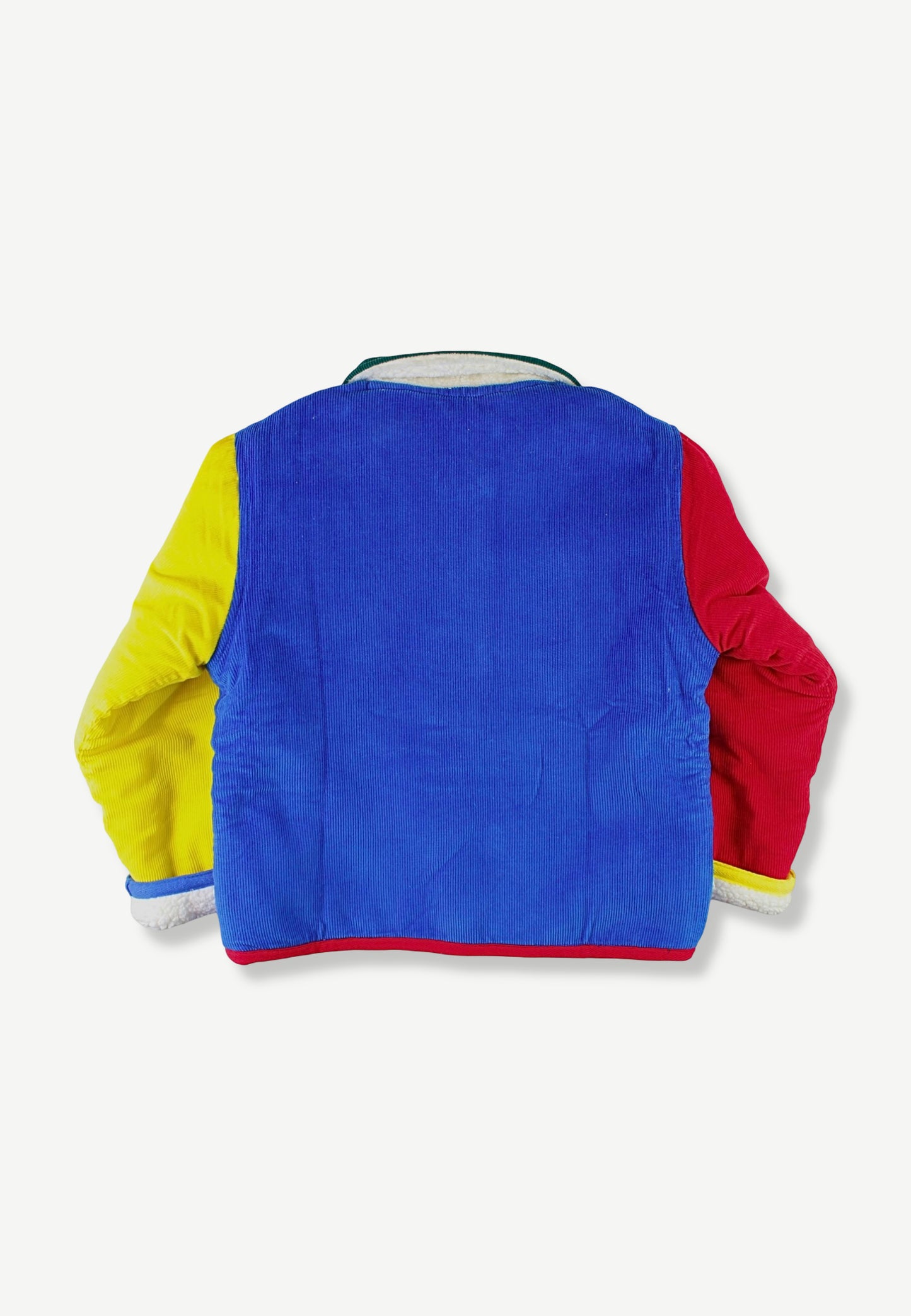 A children's color-blocked corduroy jacket shown from the back, featuring a vibrant blue back panel with yellow sleeves on the left and red sleeves on the right, set against a plain light gray background.